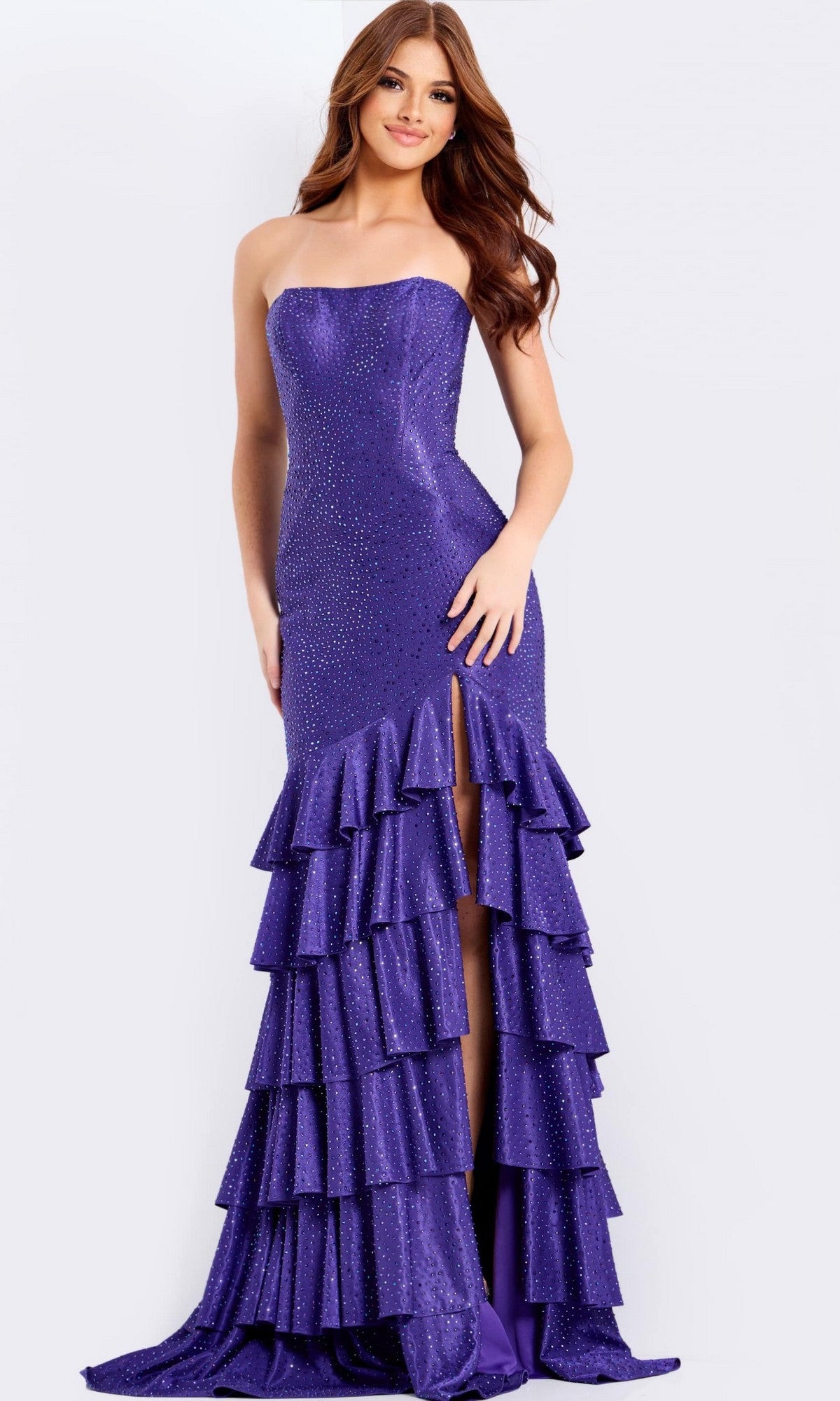 A woman models the Jovani 46909 long prom dress in purple, with a strapless neckline, sparkling rhinestone accents, and a dramatic tiered ruffle skirt cascading to the floor.